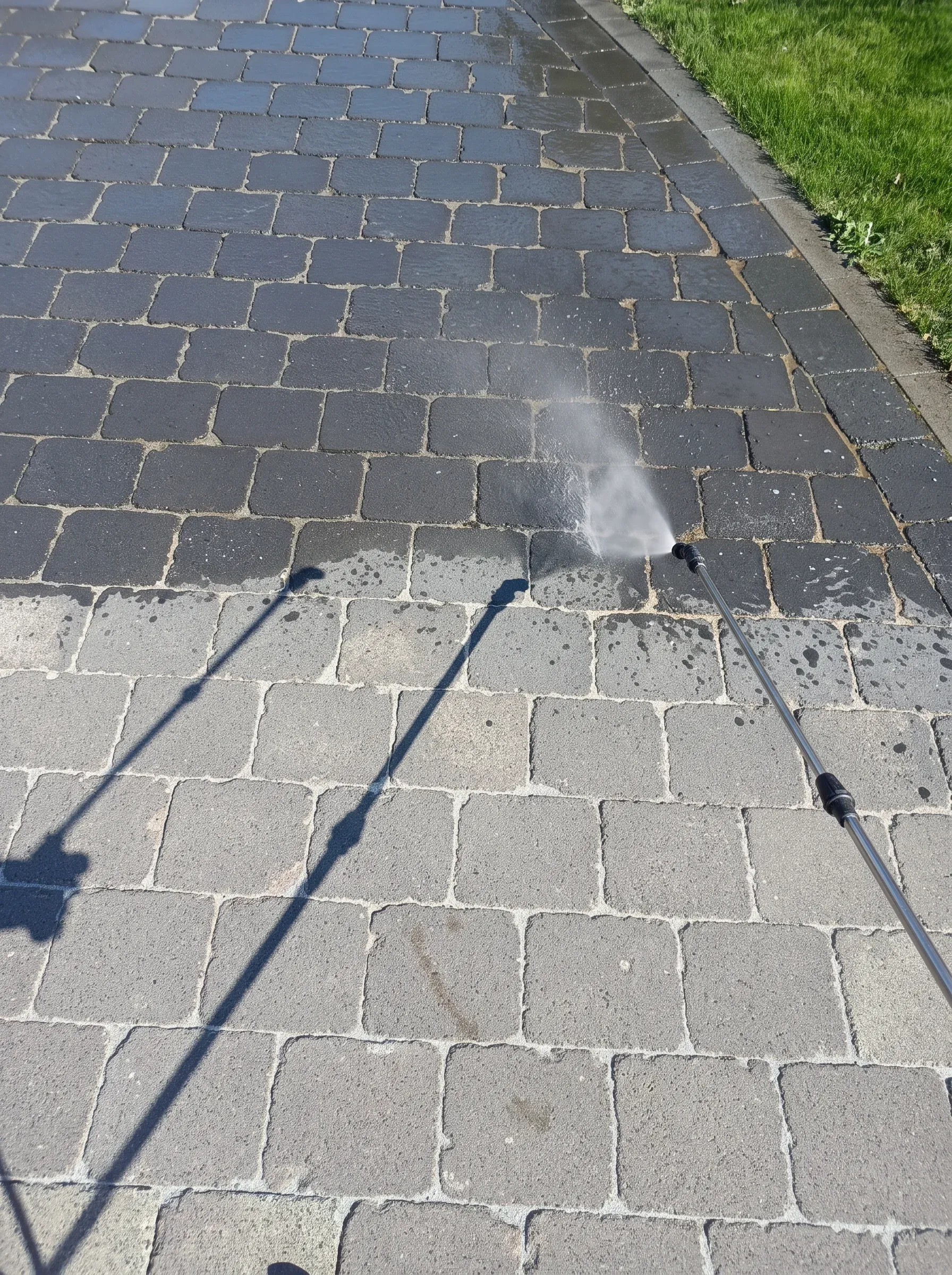 Mycie kostki brukowej za pomocą wysokociśnieniowego sprzętu, woda rozpryskuje się na powierzchni