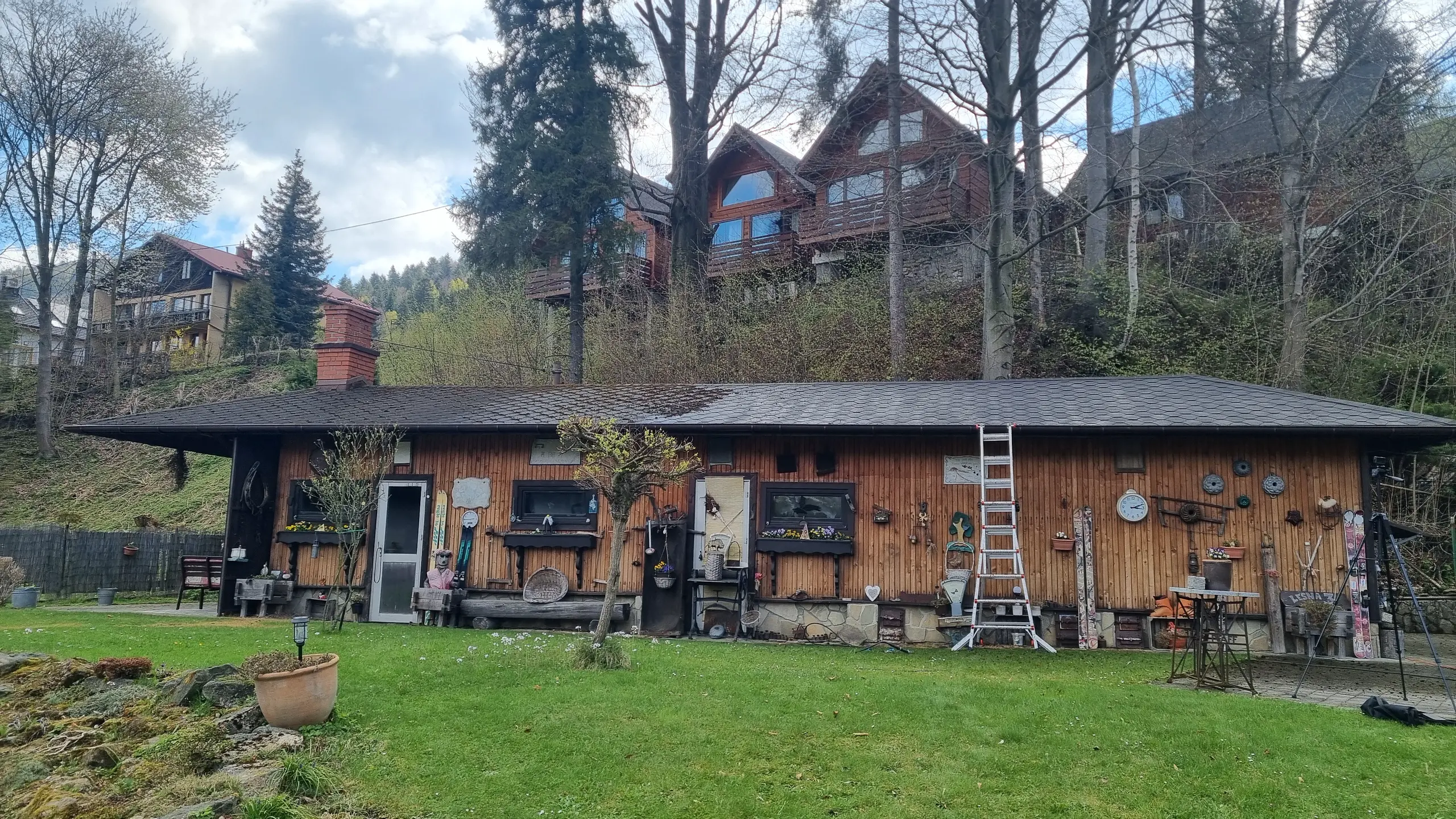 Drewniany budynek z dużym zadaszeniem, otoczony drzewami, przygotowany do mycia elewacji